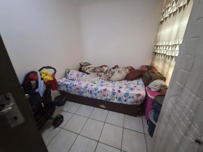 A compact bedroom featuring tiled flooring and a window with installed curtain rails.