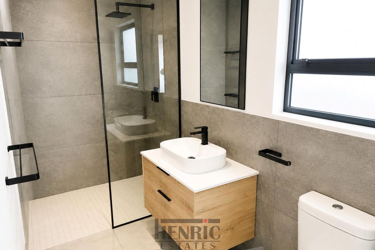 Modern bathroom featuring a walk-in shower with a glass screen, a floating wood-finish vanity with a vessel sink, and contemporary black fixtures.