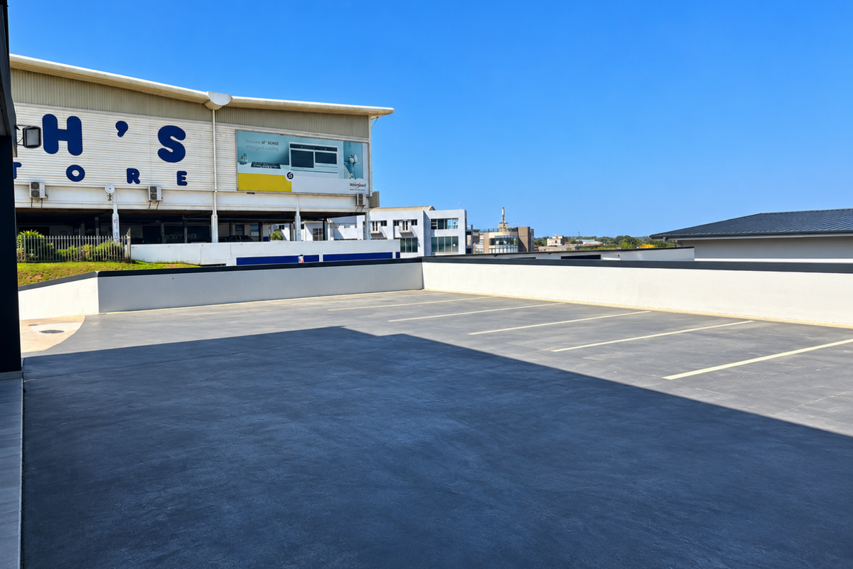 An open-air paved parking area with marked bays, situated adjacent to a commercial building structure.