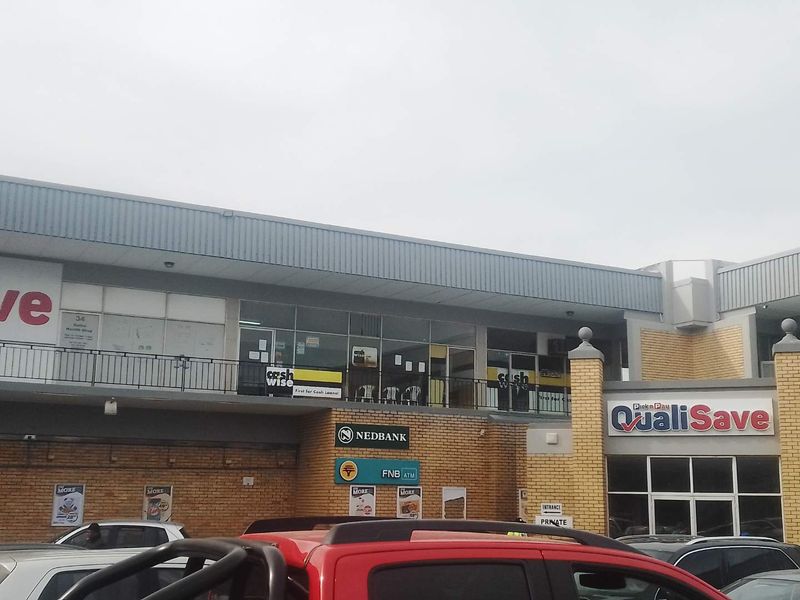 Front elevation of a commercial mixed-use building featuring brickwork, metal cladding, and prominent retail signage for various tenants and banking facilities.