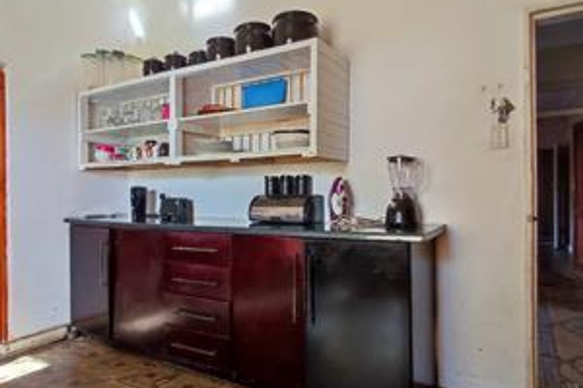A functional kitchen area featuring dark built-in cabinetry, laminate countertops, and open wall-mounted shelving, providing basic storage and preparation space.