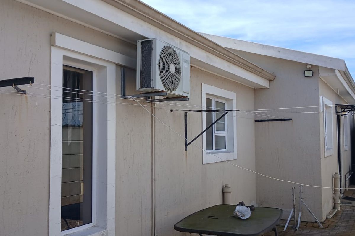 Rear exterior view of the townhouse featuring a paved courtyard, wall-mounted washing line, and an external air conditioning unit.