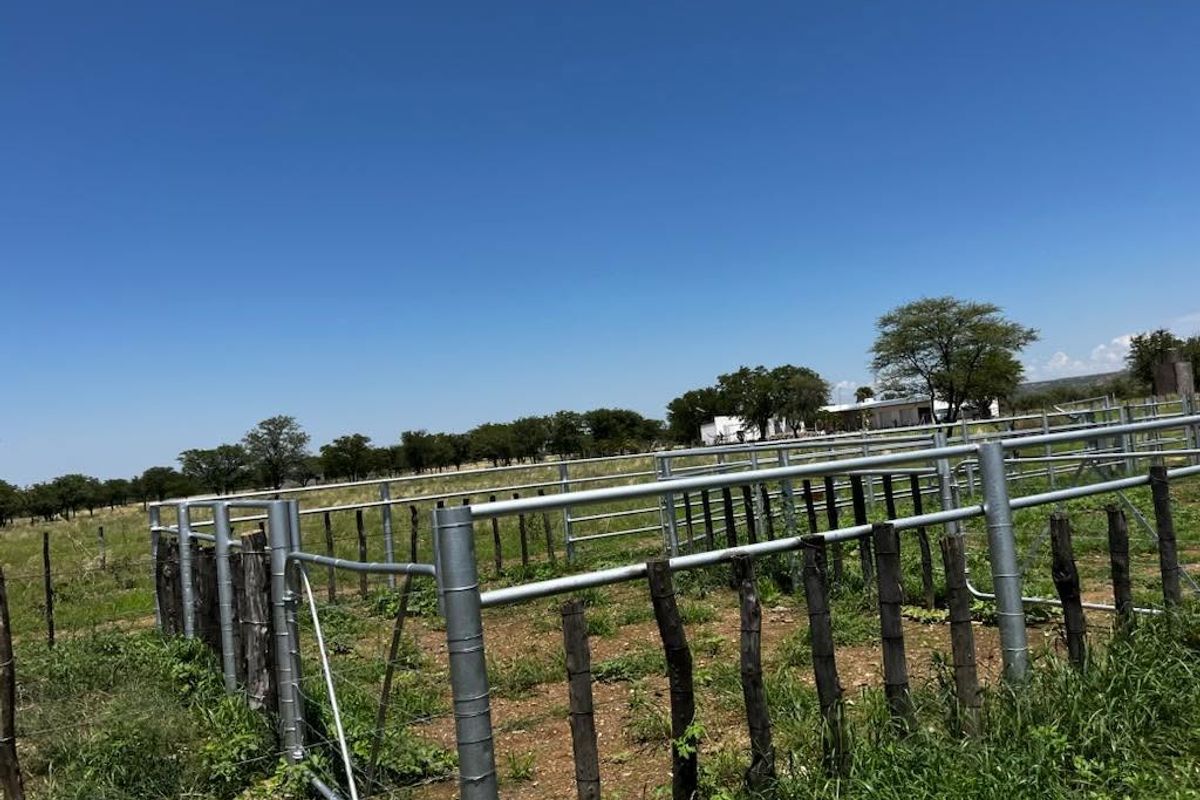 A view of the farm property featuring metal livestock fencing and wooden posts, set within an open rural landscape.