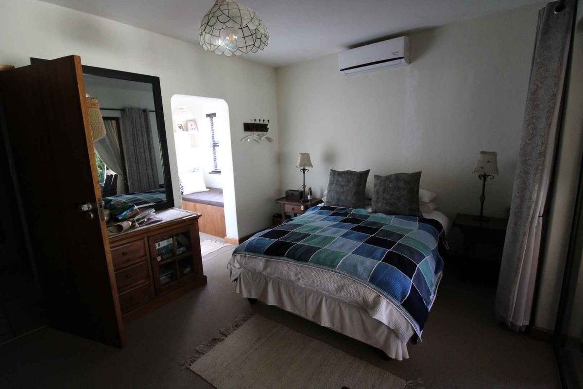 A comfortable bedroom featuring a wall-mounted air conditioning unit and a cozy built-in window seat nook.