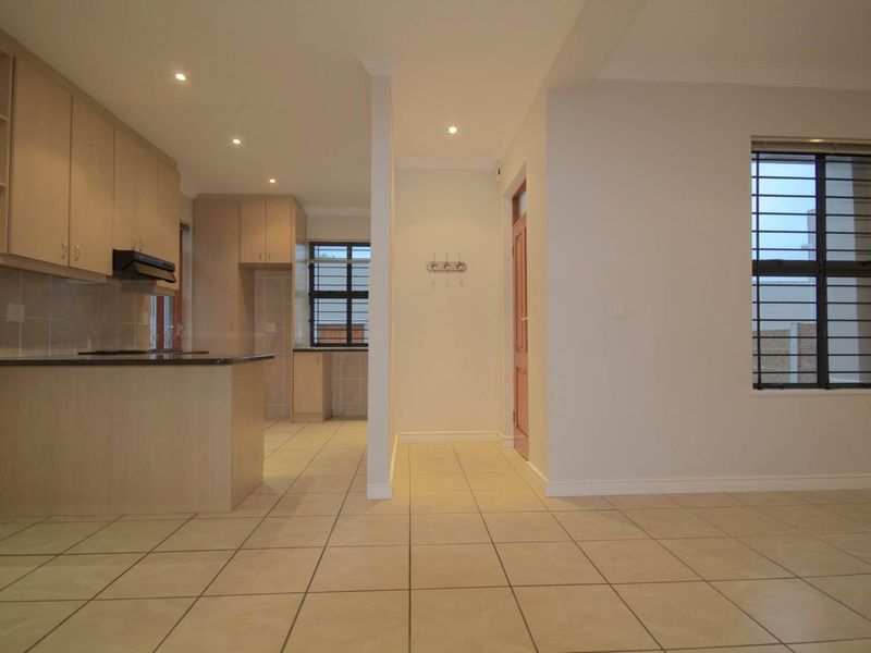 Open-plan kitchen and living area featuring neutral cabinetry, granite countertops, tiled flooring, and recessed lighting in a clean, well-maintained space.