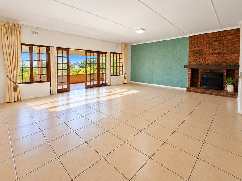 Spacious living room featuring tiled floors, a prominent exposed brick fireplace, and large sliding doors opening to an outdoor patio area.