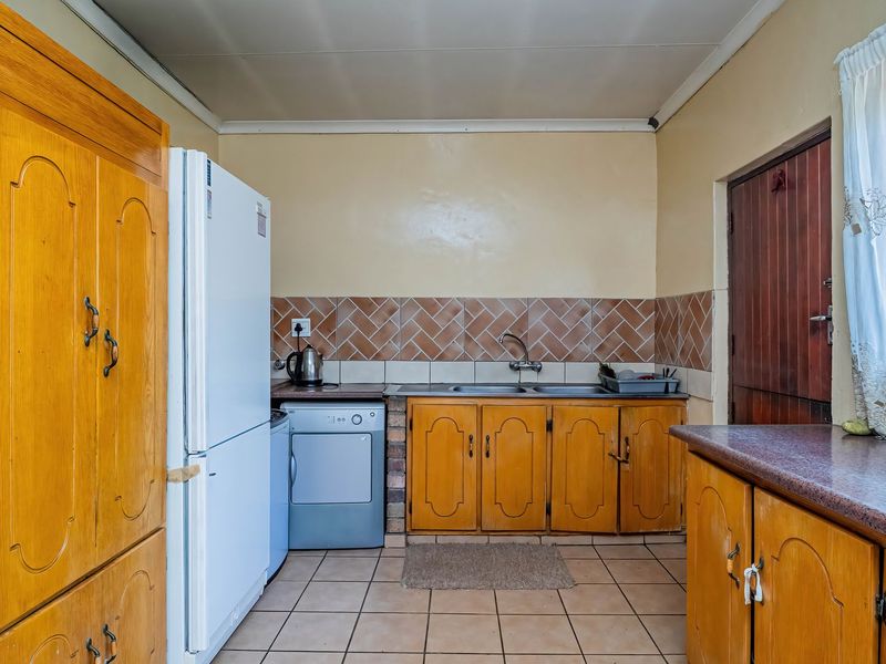A functional kitchen featuring wooden cabinetry, tiled backsplash, and double basin sink, offering a dated aesthetic ready for modernization.