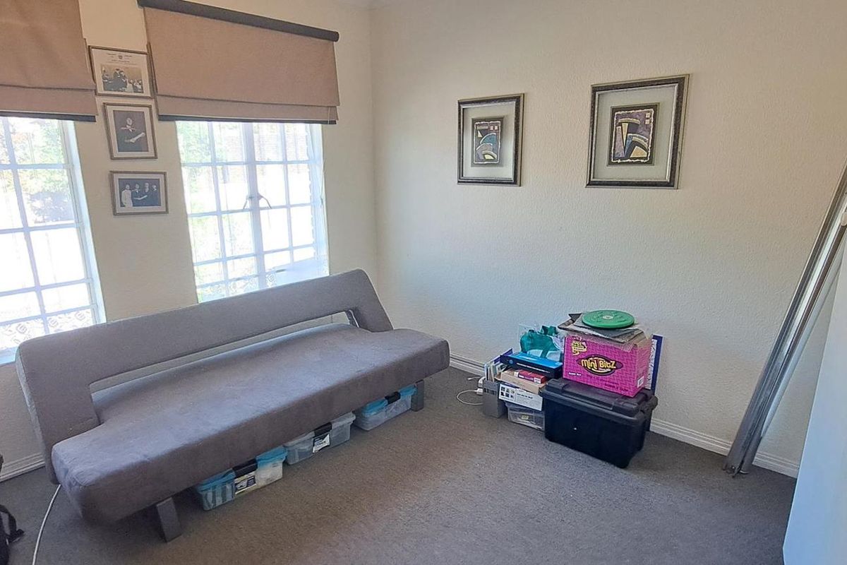 A bedroom featuring carpeted flooring, built-in cupboard storage, and dual windows fitted with roman blinds.