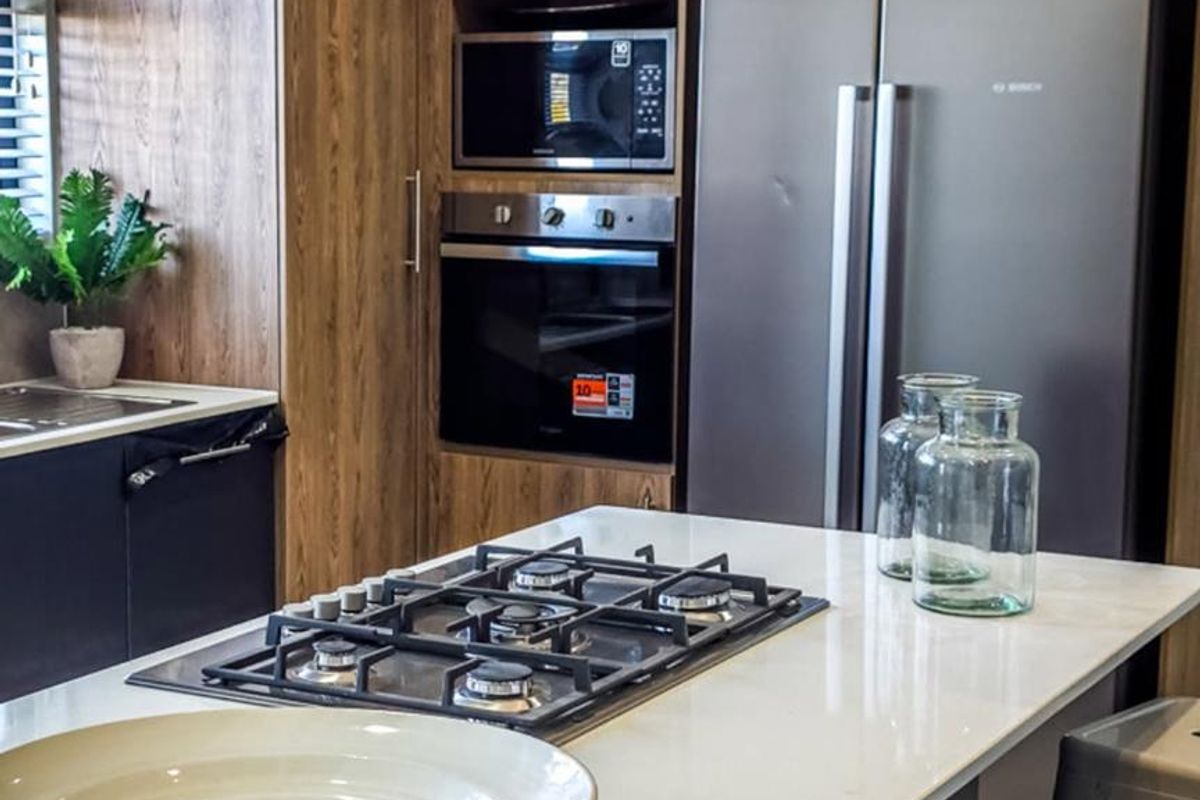 Modern kitchen featuring wood-grain cabinetry, stone countertops, a central island with a gas cooktop, and integrated built-in appliances.