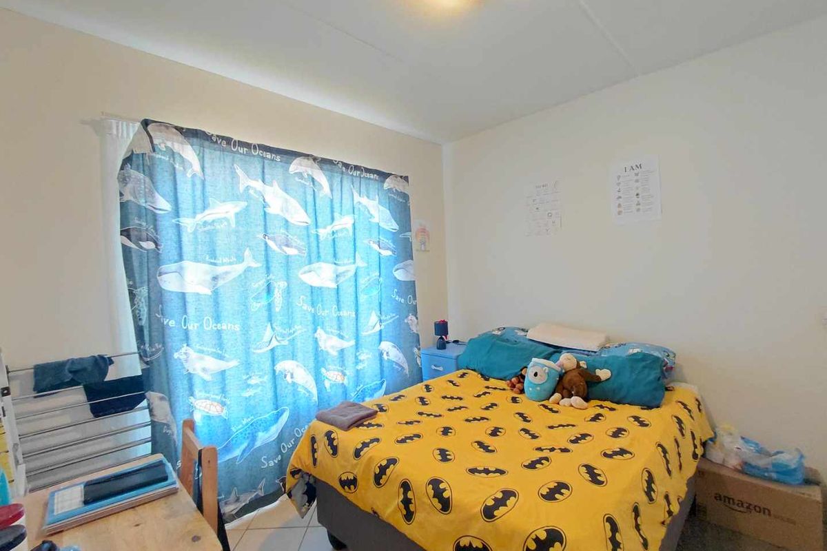 A standard bedroom featuring tiled flooring and a window with curtain treatments.