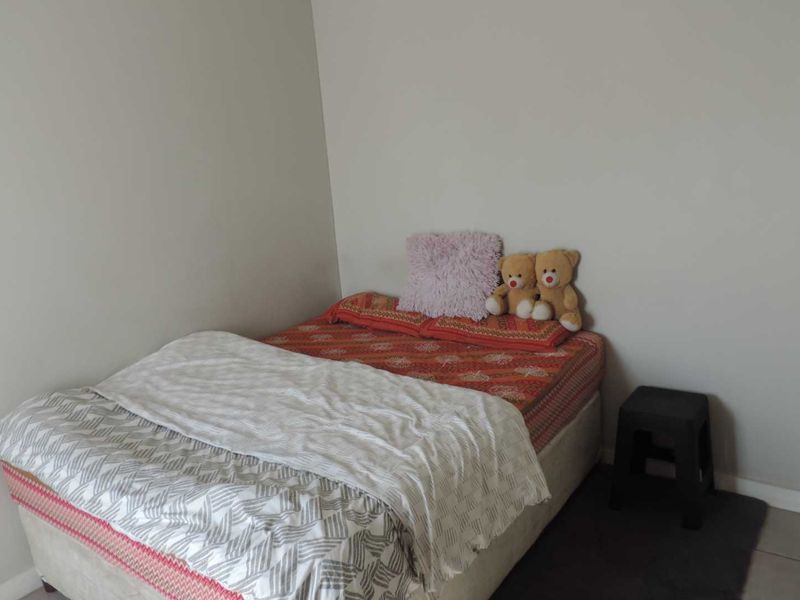 A simple bedroom featuring neutral wall finishes and tiled flooring.