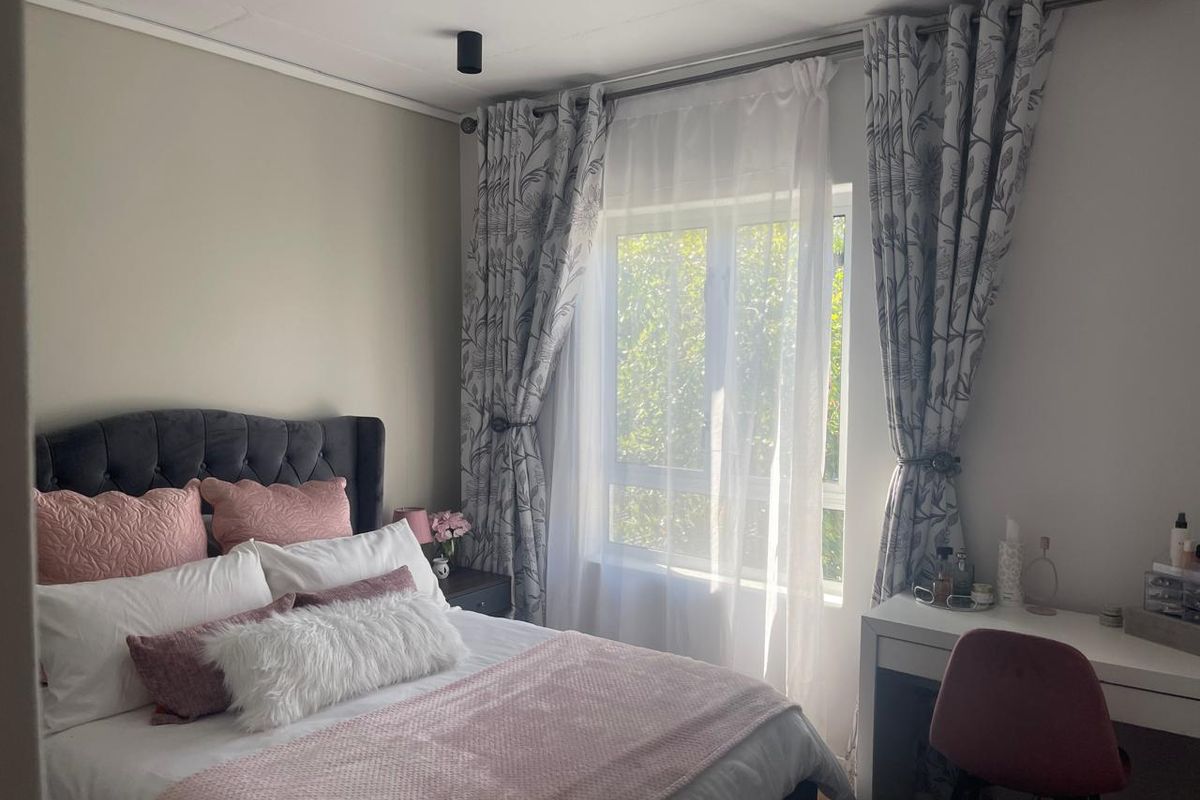 A well-maintained bedroom featuring a window with curtain rods and modern ceiling-mounted spotlights, providing a bright and comfortable living space.