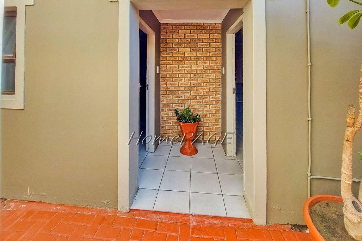 An exterior view of a doorway leading into the home, featuring a brick accent wall and tiled flooring.