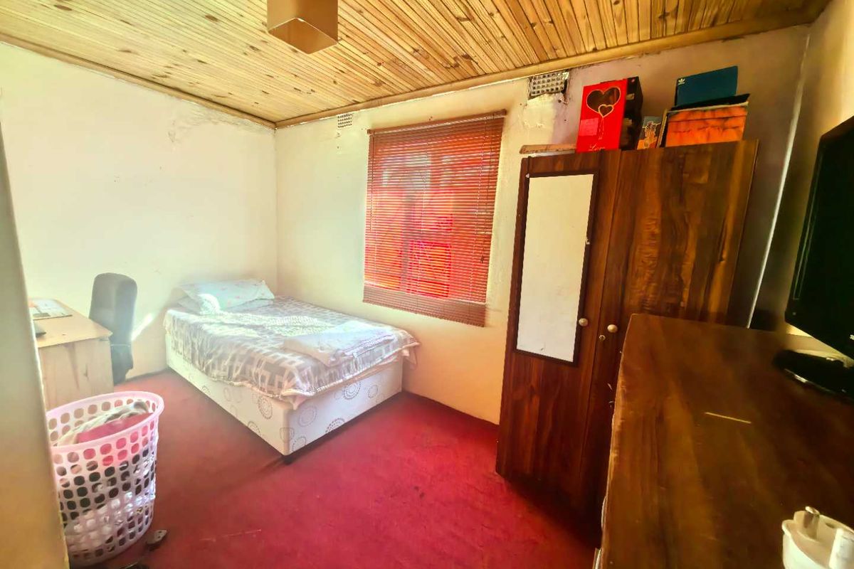 A bedroom featuring a timber-clad ceiling, red carpeting, and a window with fitted blinds.
