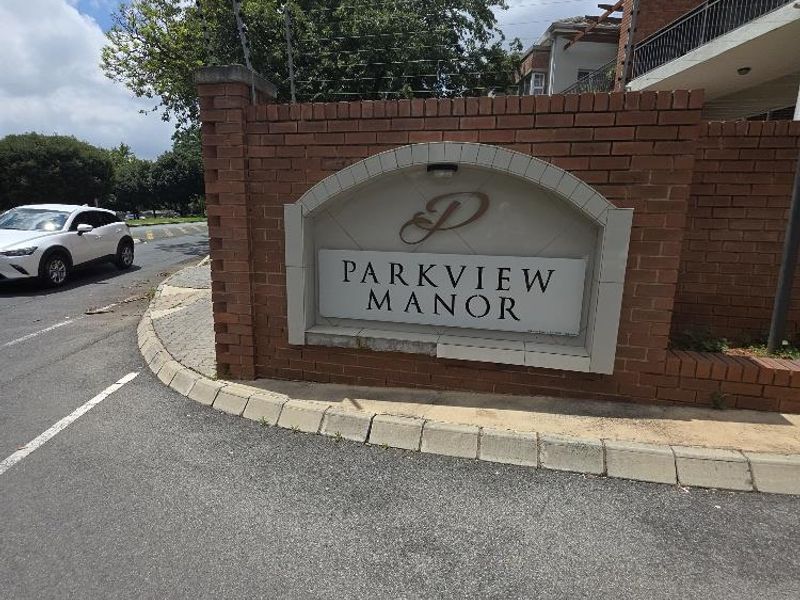 Entrance signage for Parkview Manor apartment complex featuring a brick boundary wall and electric security fencing.