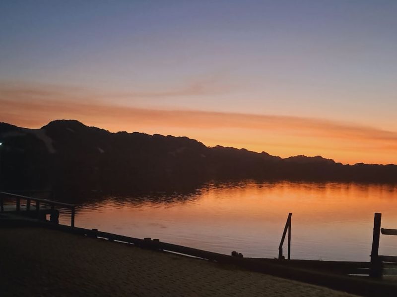A scenic sunset view over the water featuring a private jetty and timber fencing, highlighting the tranquil landscape of the property.