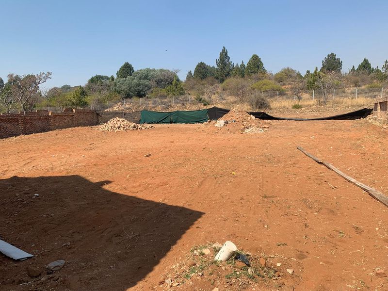 A large, undeveloped plot of land featuring a brick boundary wall and wire fencing, offering a blank canvas for landscaping or future development.