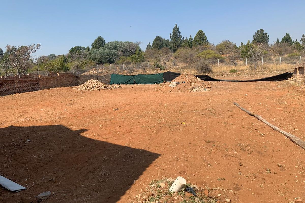 A large, undeveloped plot of land featuring a brick boundary wall and wire fencing, offering a blank canvas for landscaping or future development.