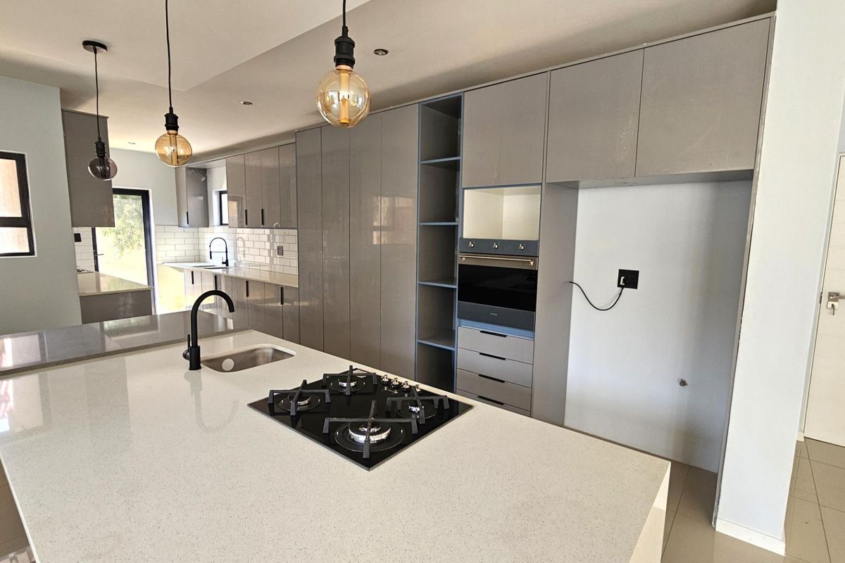 Modern kitchen featuring a large central island with a built-in gas hob, sleek cabinetry, and high-quality stone countertops.
