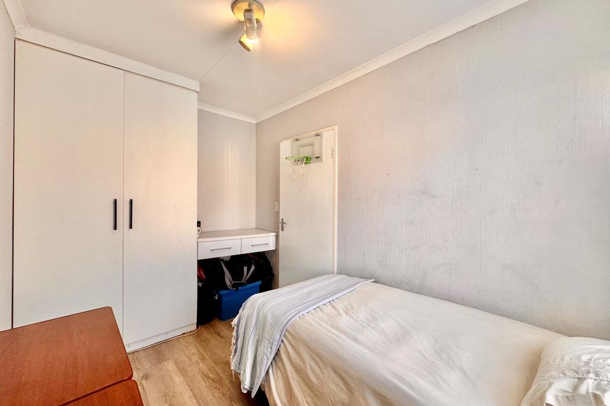 A functional bedroom featuring laminate flooring, a built-in wardrobe, and a compact built-in vanity area.