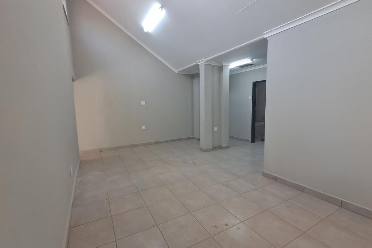 An empty, open-plan living area featuring vaulted ceilings, tiled flooring, and neutral wall finishes, offering a blank canvas for interior design.