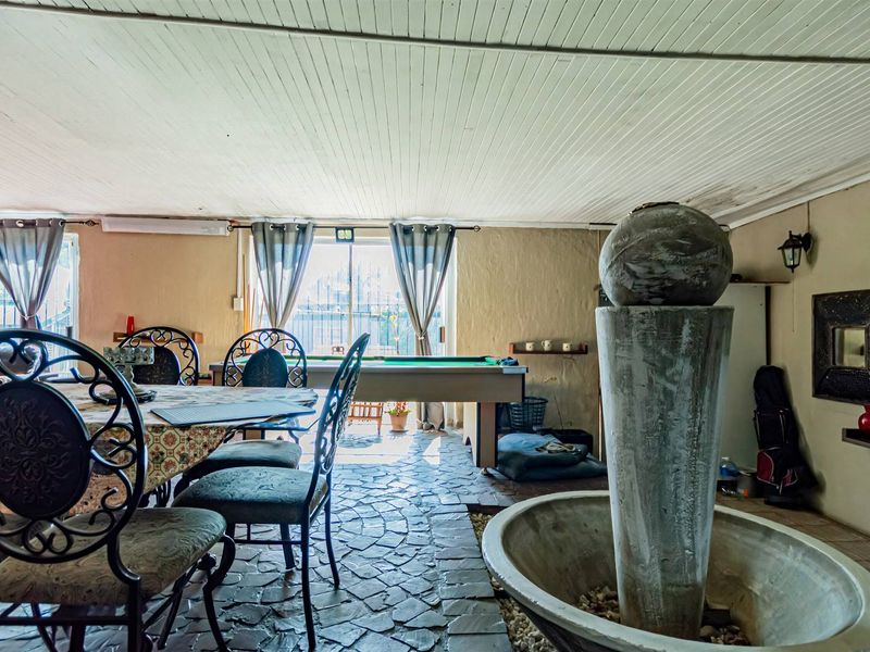 A covered patio area featuring stone flooring, a tongue and groove ceiling, and a central built-in water feature.