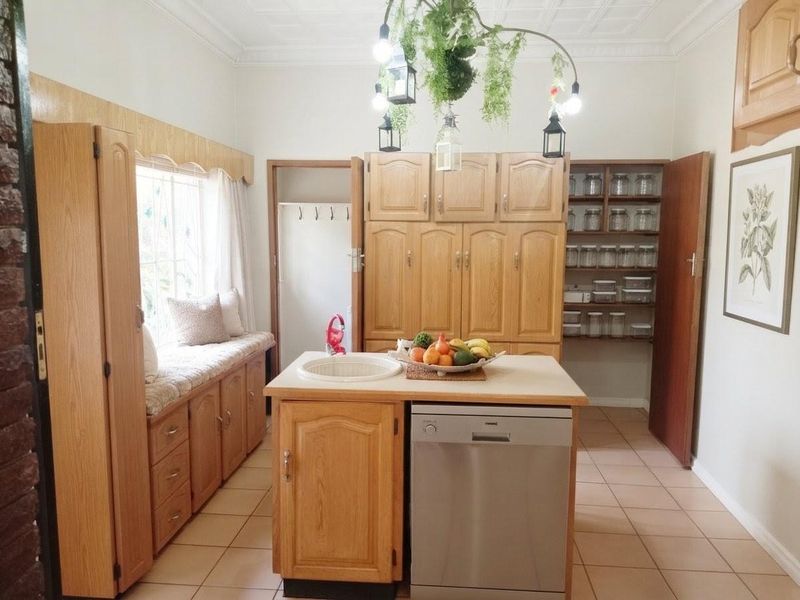 A traditional kitchen featuring wooden cabinetry, a central island with an integrated dishwasher, built-in pantry shelving, and a cozy window seat.