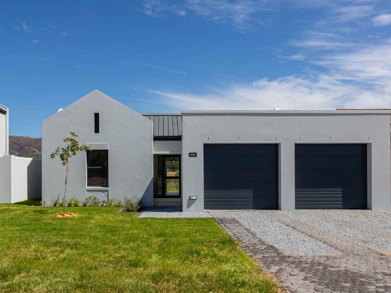 Modern single-story residence featuring a clean grey facade, double garage, paved driveway, and well-maintained front lawn.