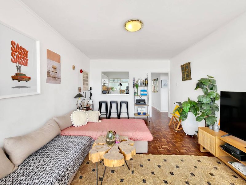 A living room featuring classic parquet flooring and a convenient pass-through window connecting to the kitchen area.