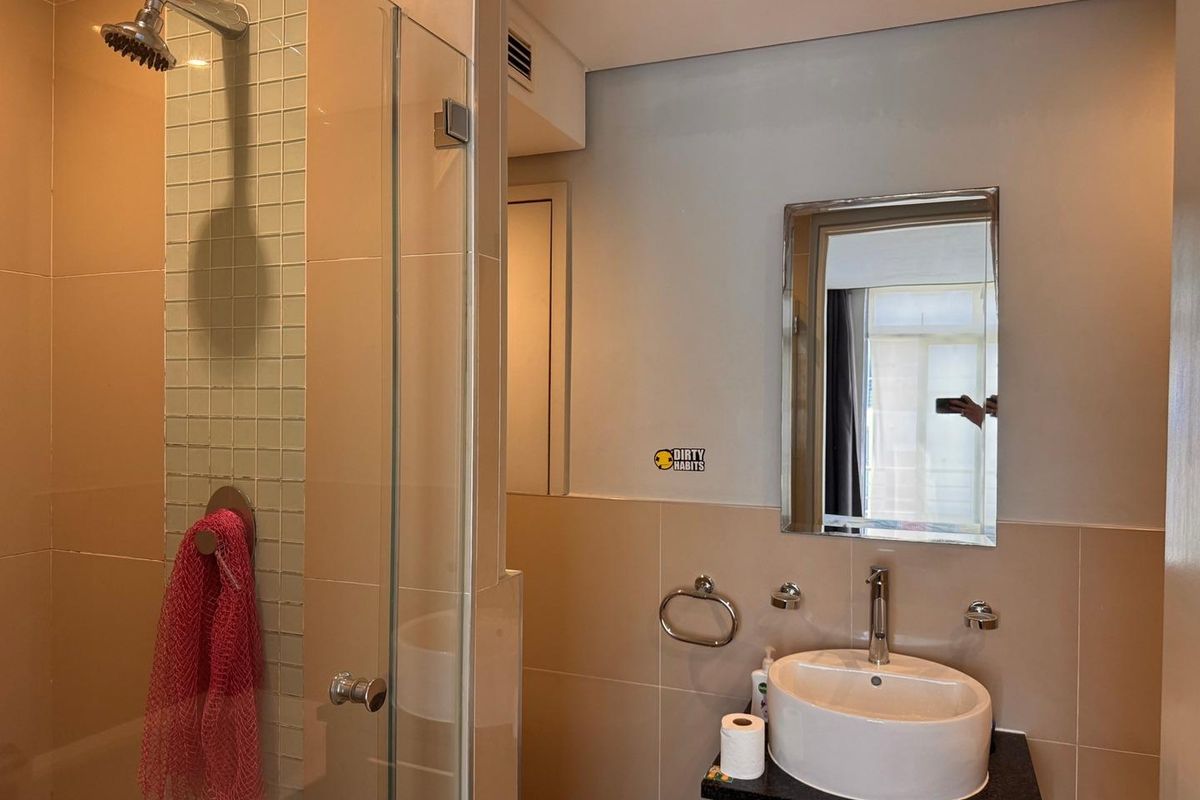 A compact bathroom featuring a glass-enclosed shower with mosaic tile accents, a modern vessel sink on a vanity, and a wall-mounted mirror.