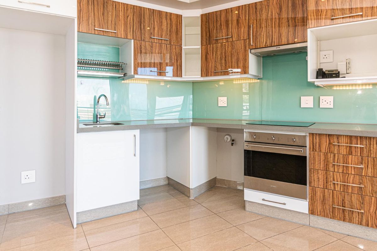 Modern kitchen featuring wood-grain cabinetry, glass splashbacks, stone countertops, and integrated stainless steel appliances including an oven and hob.