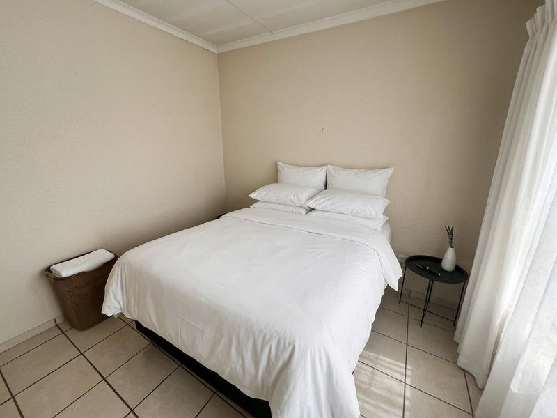 A simple bedroom featuring neutral wall tones and tiled flooring, providing a clean and functional space.
