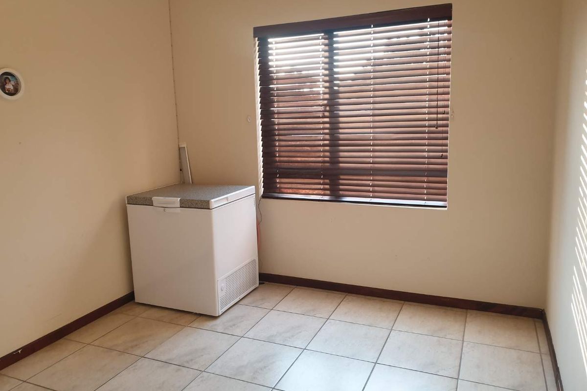 A functional room featuring tiled flooring and fitted venetian blinds, offering a neutral space suitable for various uses.