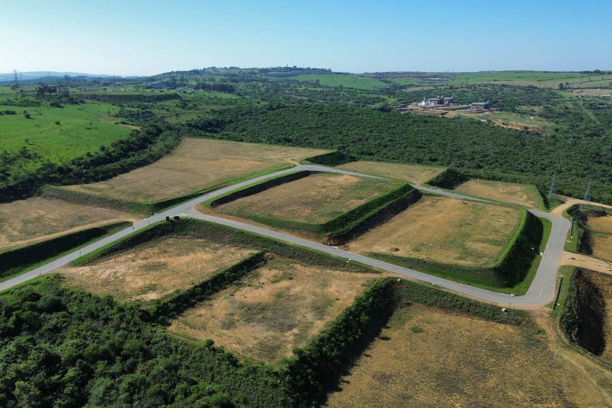 Aerial view of an industrial development site featuring leveled land platforms, established retaining embankments, and paved access roads within a green landscape.