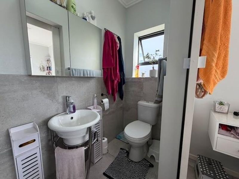 A compact bathroom featuring a pedestal basin, toilet, and a mirrored medicine cabinet with tiled wall finishes.