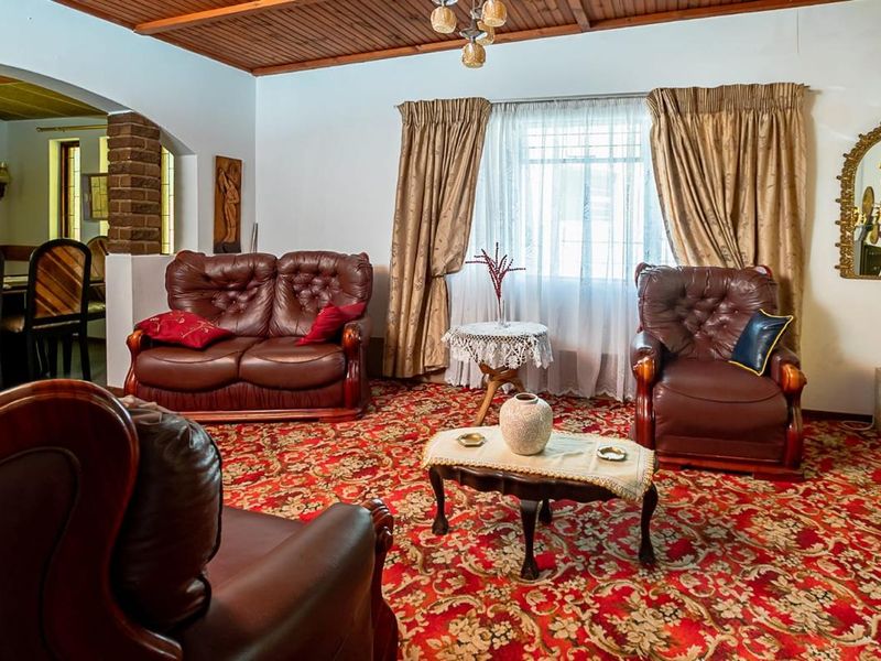 A traditional living room featuring a timber-clad ceiling, brick feature pillar, and an archway leading to the dining area.