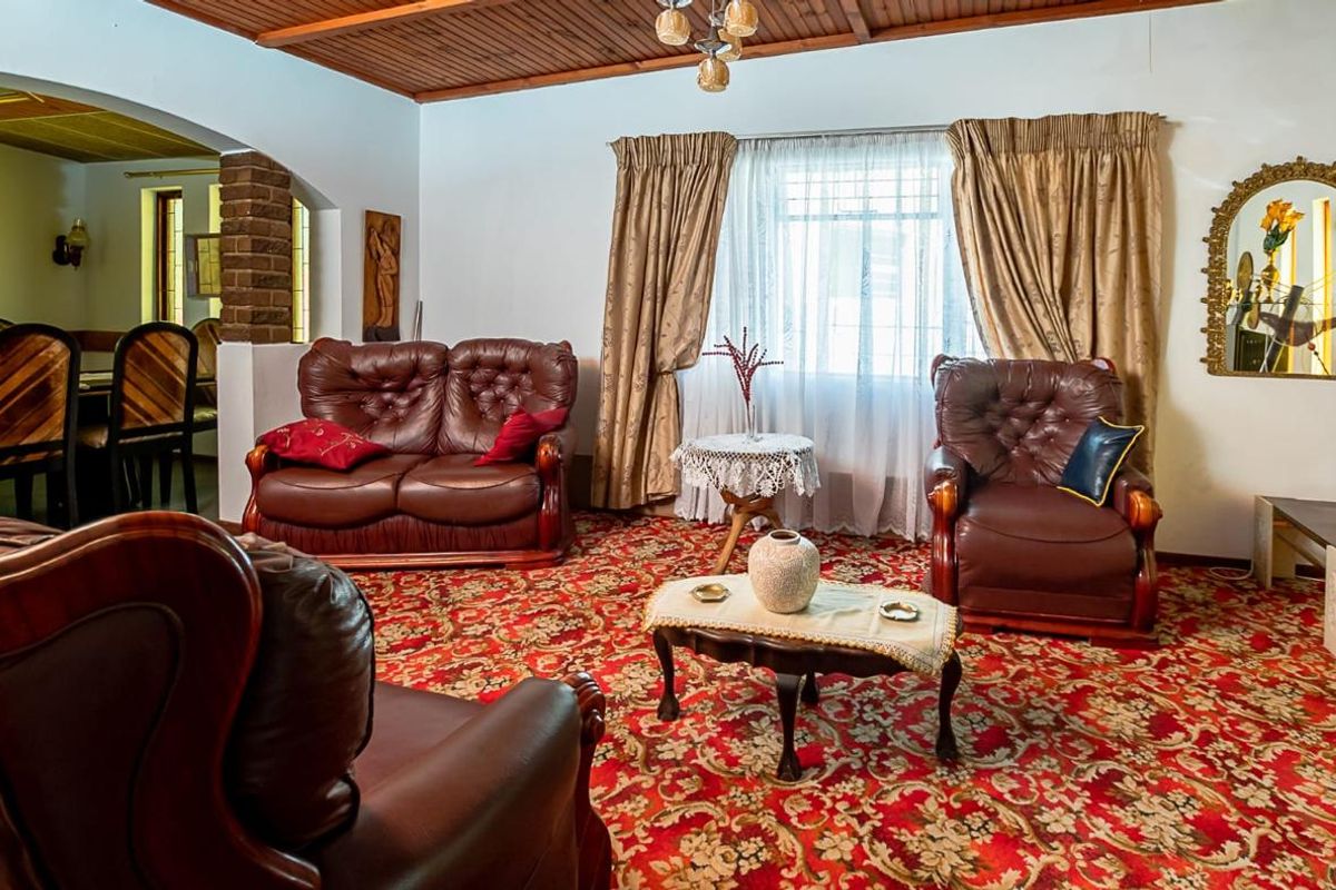 A traditional living room featuring a timber-clad ceiling, brick feature pillar, and an archway leading to the dining area.