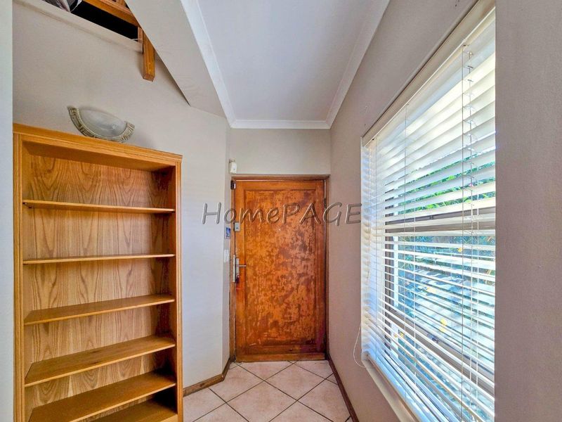 Entrance area featuring tiled flooring, a wooden door, and a staircase leading to the upper level.