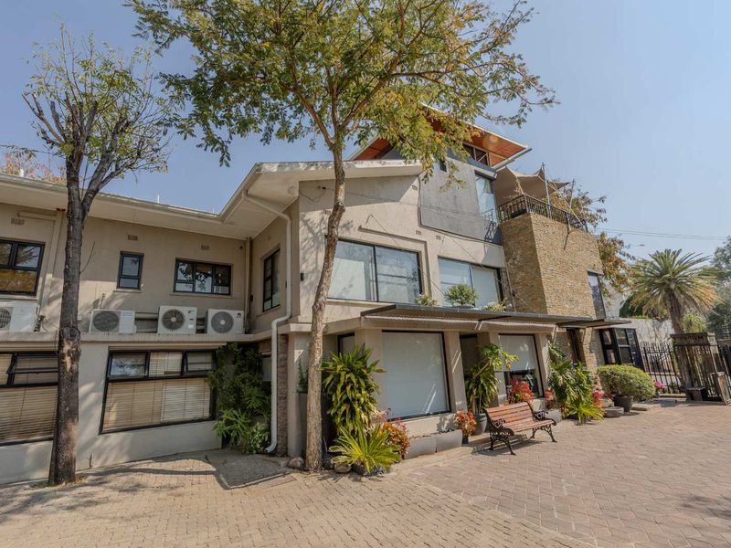 Front elevation of a multi-story residential property featuring stone cladding, paved driveway, and aluminum window frames.