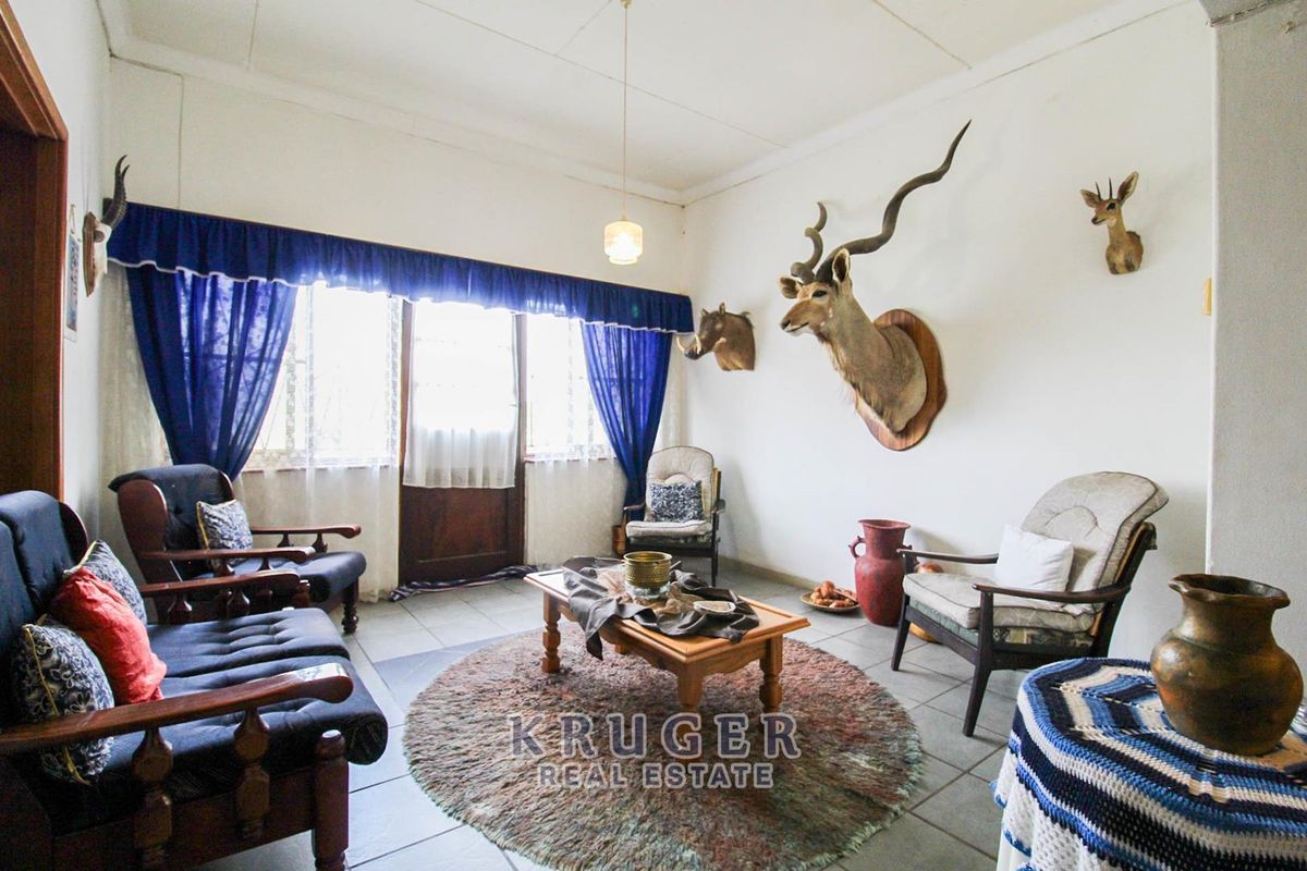 A living room featuring tiled flooring, a large window with natural light, and a central pendant light fixture.