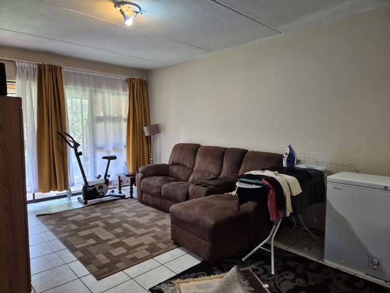A living room featuring tiled flooring and a large sliding glass door providing natural light and access to the exterior.