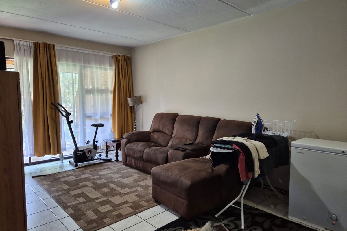 A living room featuring tiled flooring and a large sliding glass door providing natural light and access to the exterior.
