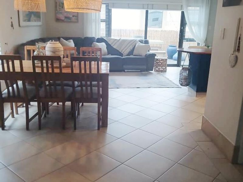 Open-plan living and dining area featuring tiled flooring, pendant lighting, and sliding glass doors leading to an outdoor space.