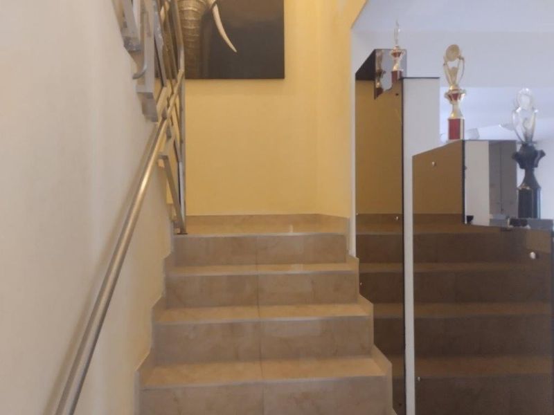 Interior staircase featuring tiled steps and a metal handrail, leading to an upper level with decorative wall accents.