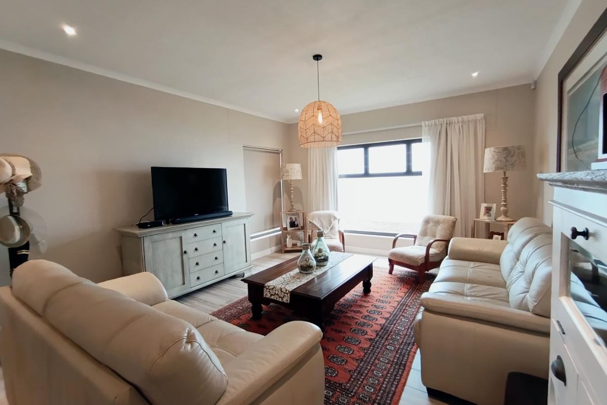 A well-maintained living room featuring neutral wall tones, recessed downlighting, and modern laminate flooring, creating a comfortable and inviting atmosphere.