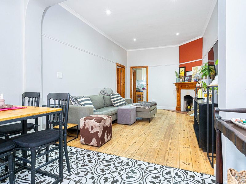 Open plan living and dining area featuring original timber flooring, a decorative fireplace, and classic architectural details including a picture rail and archway.