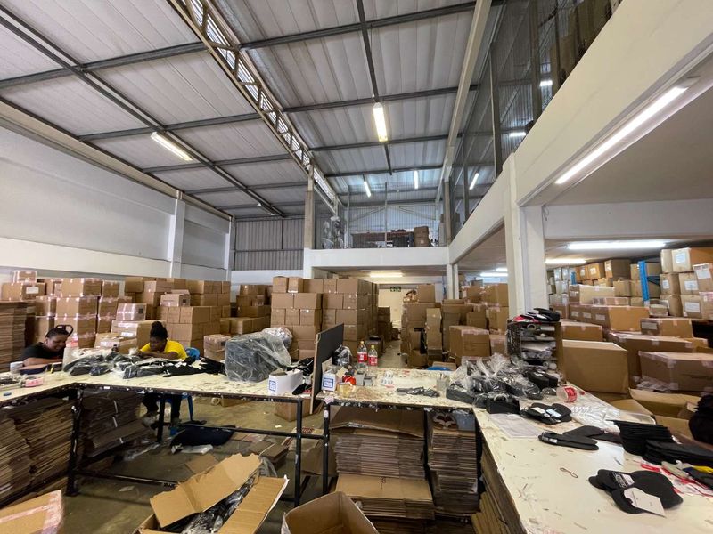 A large industrial utility space featuring high ceilings with exposed steel trusses, a mezzanine level, and concrete flooring, currently utilized for storage and operations.