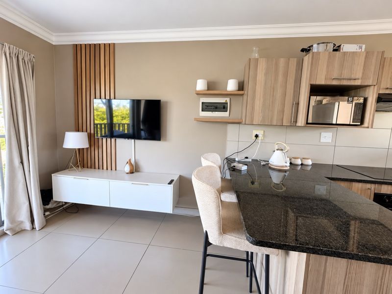 Modern open-plan living and kitchen area featuring a granite breakfast bar, timber slat wall detailing, and contemporary built-in cabinetry.
