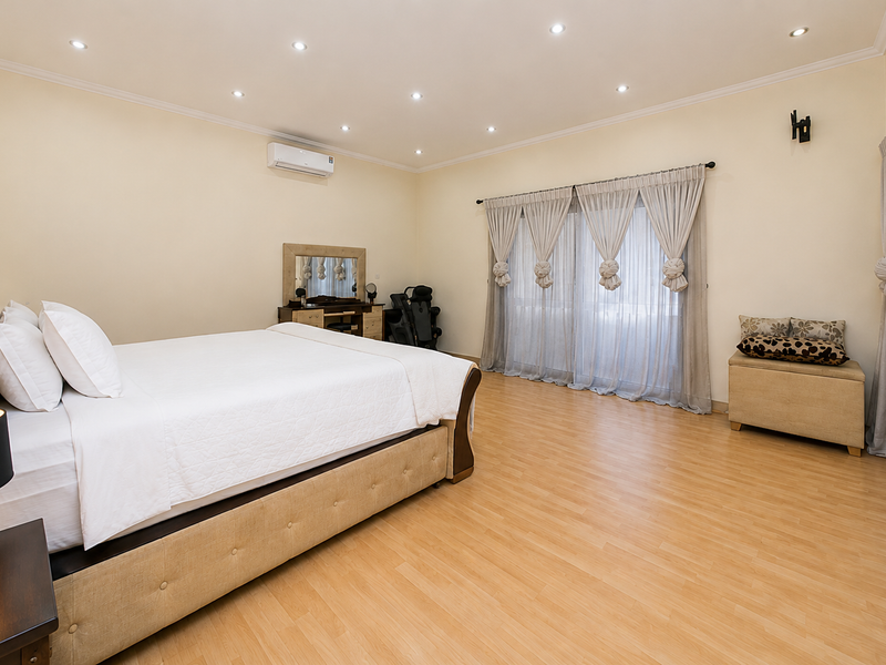 Spacious bedroom featuring light laminate flooring, recessed downlighting, a split-system air conditioner, and large sliding glass doors providing access to the exterior.