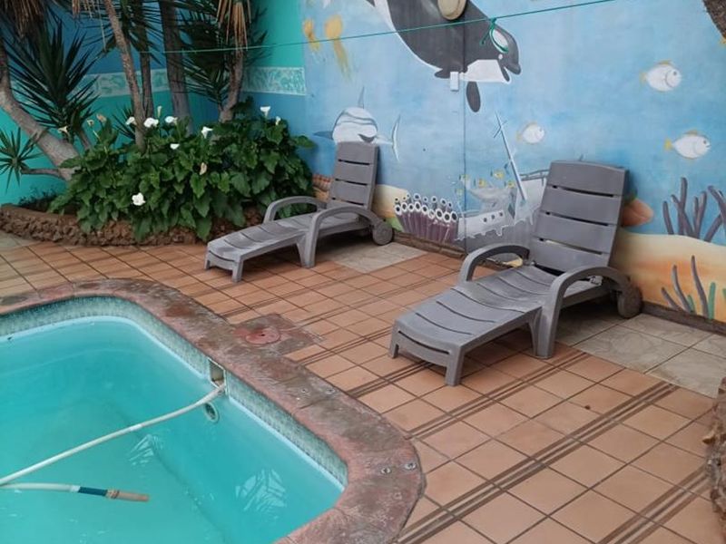 Outdoor pool area featuring a tiled surround and a decorative mural on the boundary wall, providing a functional space for relaxation.